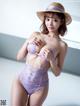 A woman in a purple lingerie and a straw hat.