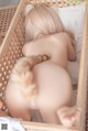 A naked woman laying in a wooden crib with a cat tail.