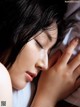 A woman laying in bed with her eyes closed and her hand on her face.