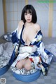 A woman in a blue and white kimono sitting on a bed.