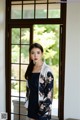 A woman standing in front of a window wearing a black dress.