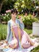 A woman in a pink and blue hanbok sitting on the ground.