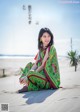 A woman sitting on a sandy beach next to the ocean.