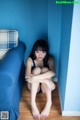 A woman sitting on the floor in front of a blue couch.