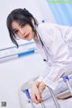 A woman in a white lab coat sitting on a hospital bed.