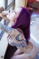 A woman with purple hair and a tattoo on her arm.