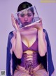 A woman in a purple lingerie holding a clear box over her face.