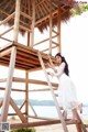 A woman in a white dress standing on a wooden ladder.