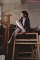 A woman sitting on top of a wooden chair.